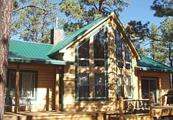 Cabin Kit Model - Chicory-3BR with pine log siding, interior paneling, wood floors, stone fireplace.